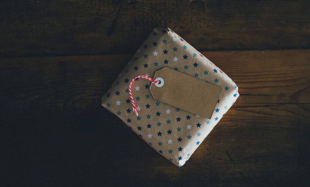 Present wrapped in star-patterned paper with blank tag on wooden table background