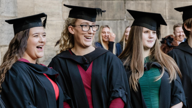 Graduates in caps and gowns celebrating their achievement at university ceremony, smiling and joyful