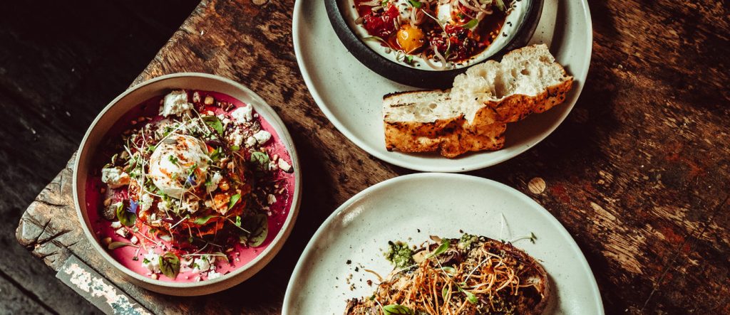Three delicious plates of colourful gourmet dishes on rustic wooden table