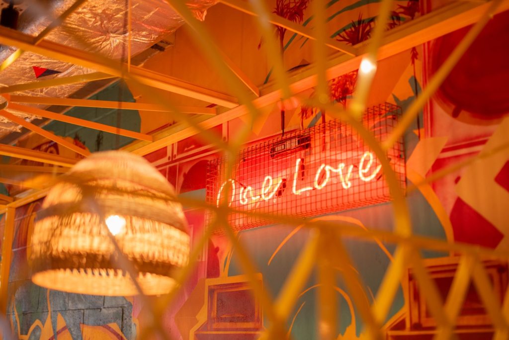 Warm, inviting bar interior with vibrant red neon sign and soft ambient lighting creating a cosy atmosphere