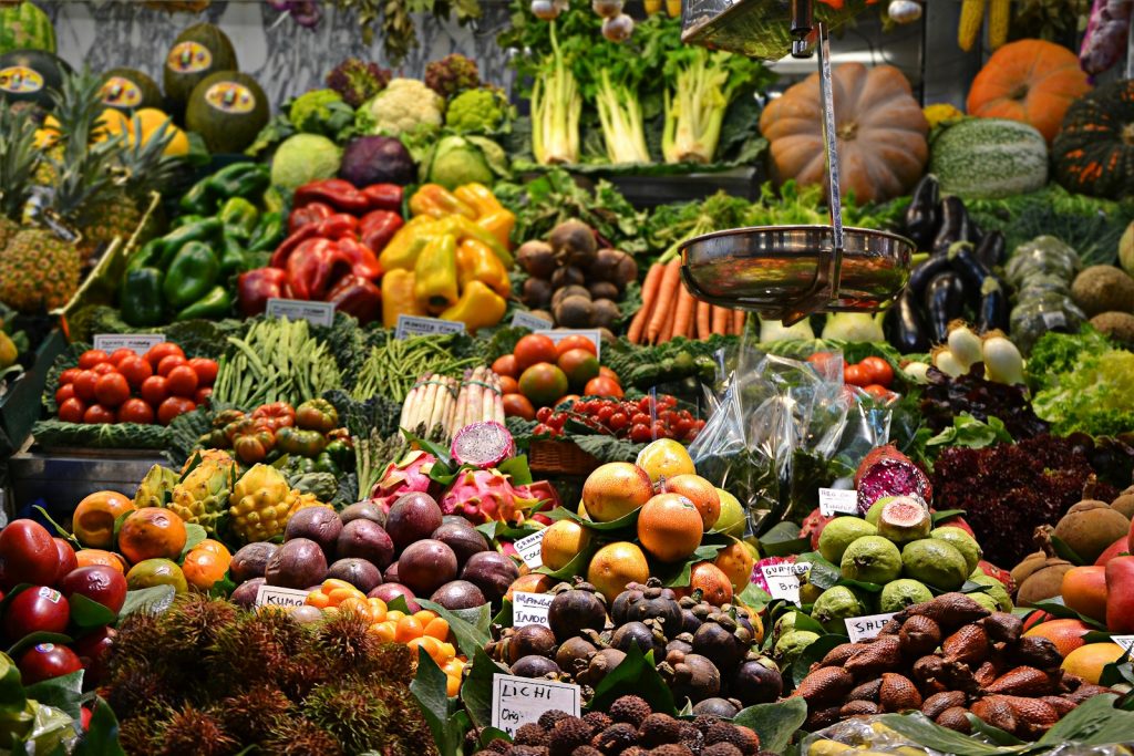 Colourful fresh fruits and vegetables at a market stall with produce variety including tomatoes, peppers, and greens