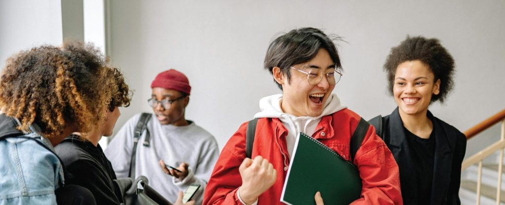 Group of diverse students laughing and chatting indoors, capturing a moment of joy and camaraderie