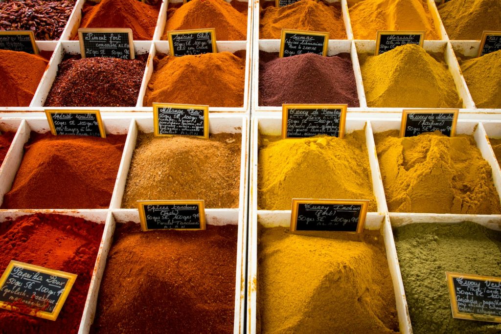 Assorted colourful spices displayed in a market, arranged in square sections with labels for each type